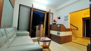 A modern living room with a sofa, a small round table, and a reception desk. - Ashray The Living Entity  (Bidhannagar)