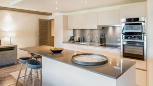 A modern kitchen with a central island, stainless steel appliances, and bar stools. - Wifi, 150m from ski slopes, 1st floor, view mountain, sauna, terrace, balcony, fireplace or stove (Courchevel)