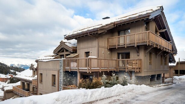 Un edificio de madera de varios pisos con balcones, rodeado de nieve.
