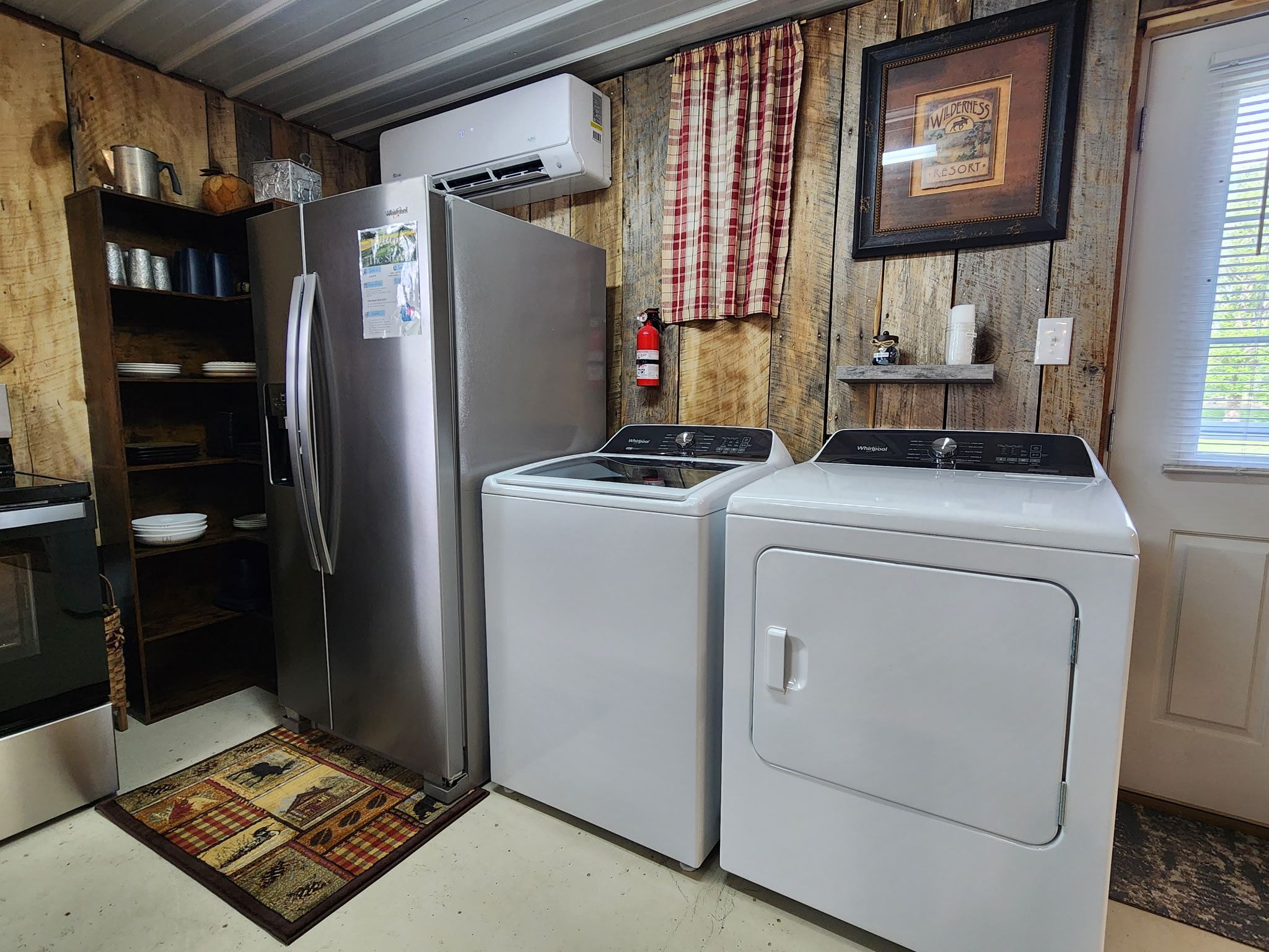 A compact kitchen with a refrigerator, washer, dryer, and a small shelf with items.