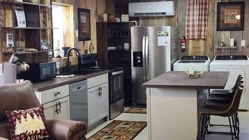 Cozinha compacta com ilha central, eletrodomésticos de aço inoxidável e interior em madeira rústica.