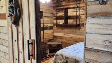 Um quarto rústico de madeira com uma cama, um ventilador de teto e uma porta de madeira.