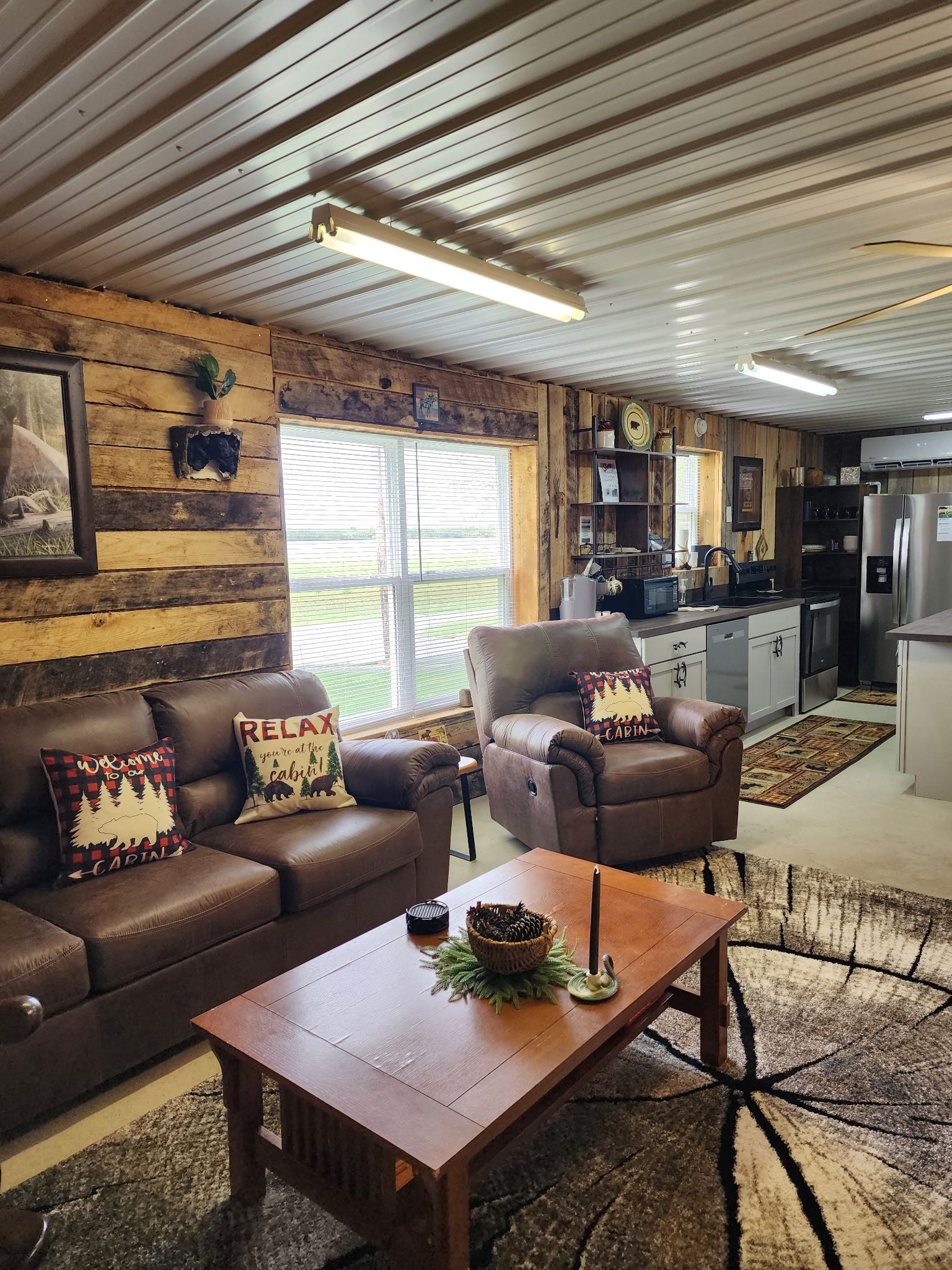 Um interior acolhedor estilo cabana, com parede de madeira, sofá, mesa de centro e área de cozinha.