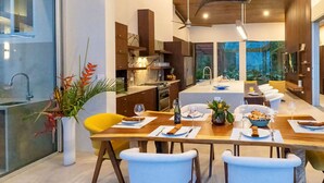 Een moderne keuken met donkere kastjes, een centraal eiland en hangende lampen.