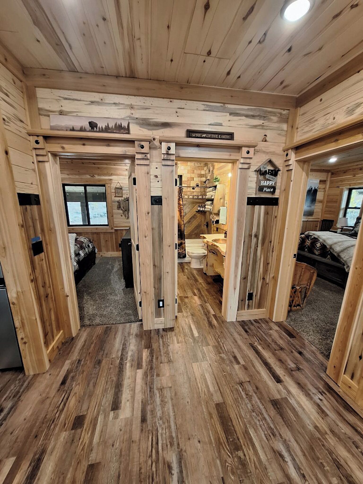 Interior de uma cabana, com um corredor central que leva a um banheiro e um quarto.