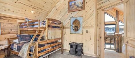 A wooden cabin interior with bunk beds, a small table, and a window with a view.