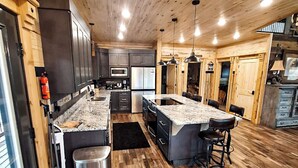 A spacious kitchen with wooden flooring, granite countertops, and modern appliances.
