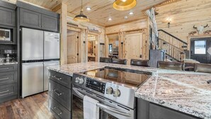 A modern kitchen with granite countertops, stainless steel appliances, and wooden paneling.
