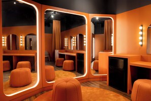 Una habitación moderna con decoración naranja, paredes espejadas, asientos y un refrigerador.