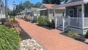 A row of single-story houses with front porches, a brick pathway, and a small garden area. - Coastal Estate (Cape May)