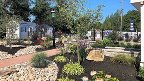 A garden with a pathway, rocks, and various plants. - Coastal Estate (Cape May)