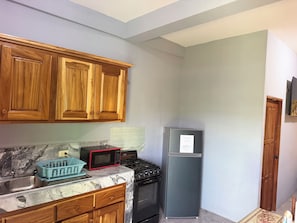 A kitchen with wooden cabinets, a microwave, a refrigerator, and a stove.