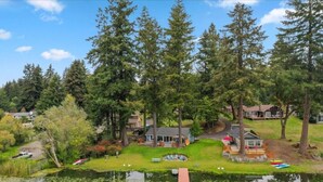 Une propriété au bord du lac, dotée d’un quai, d’un petit bateau et d’un chalet entouré de grands arbres.