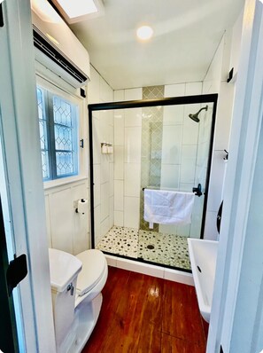 Bathroom features a glass-enclosed shower, toilet, and patterned tile floor.