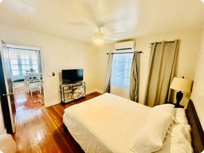Relax in a spacious room with a large bed, flat-screen TV, and ceiling fan.