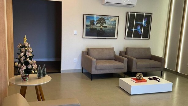A modern living room with two sofas, a coffee table, and a small Christmas tree. - Hotel Iaguara (Coxim)