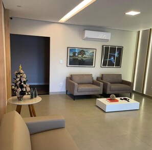 A modern living room with two sofas, a coffee table, and a small Christmas tree. - Hotel Iaguara (Coxim)