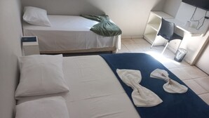 A hotel room with a bed, a desk, a chair, a TV, and a trash bin. - Hotel Iaguara (Coxim)