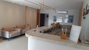 A modern hotel lobby with a reception desk, seating area, and artwork on the walls. - Hotel Iaguara (Coxim)