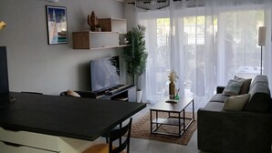 Una sala moderna con sofá, una mesa de comedor y una zona de cocina con televisor.