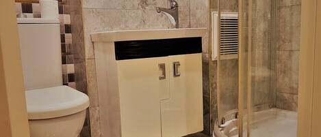 Un baño con inodoro, lavamanos con espejo y cabina de ducha de vidrio.