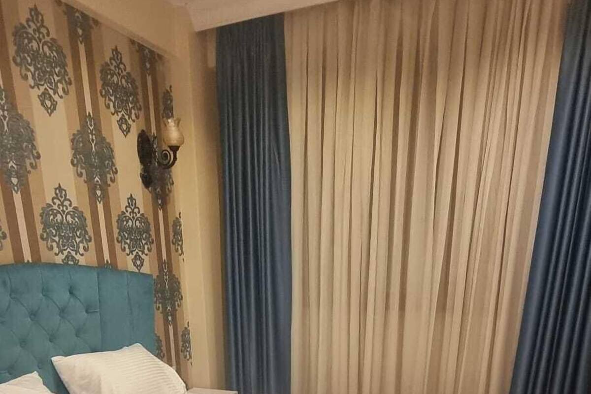 A bedroom with a large bed, a blue headboard, and a wooden floor.