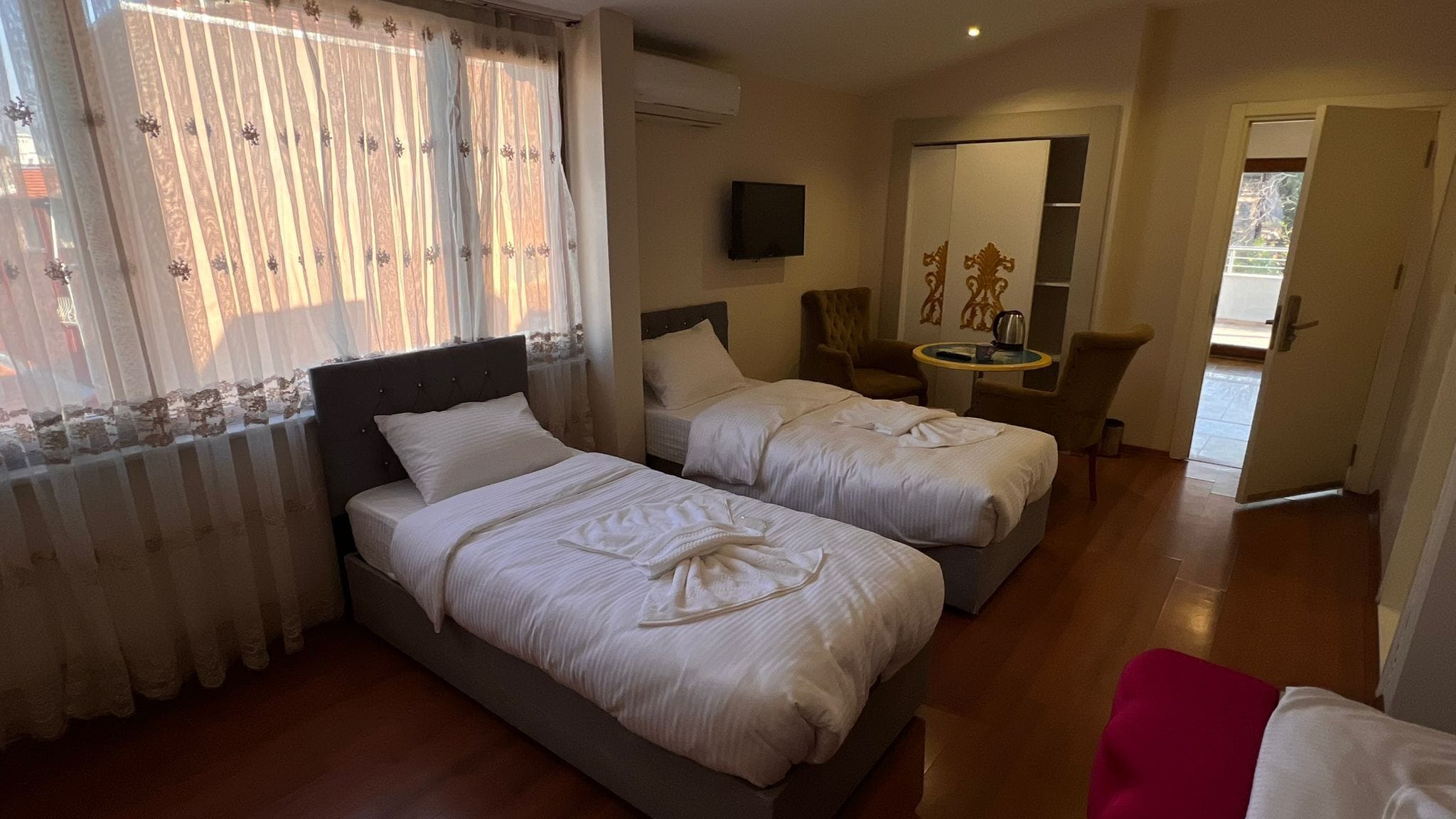 A hotel room with two beds, a TV, a small table, and a chair.