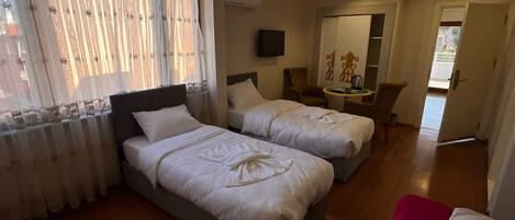 A hotel room with two beds, a TV, a small table, and a chair.