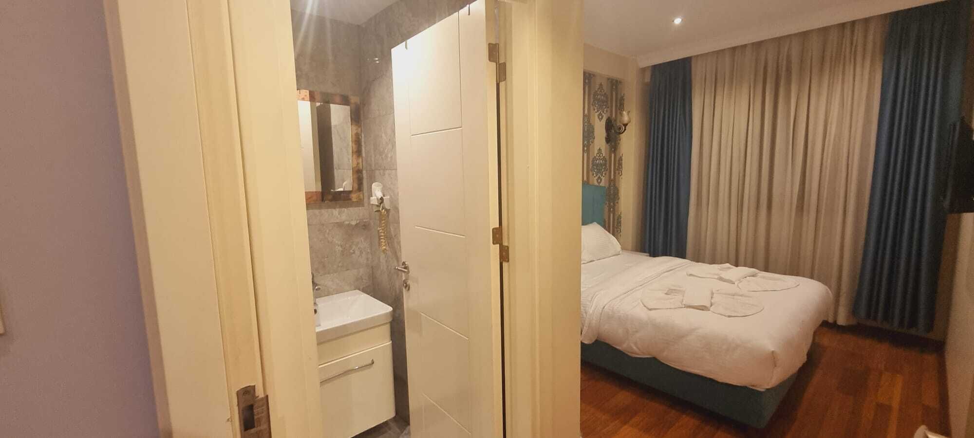 A hotel room with a bed, a bathroom, and a view of the outside.