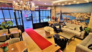 A hotel lobby with a red carpet, seating area, and a large cityscape mural. - By Historyal Hotel Due (Istanbul)