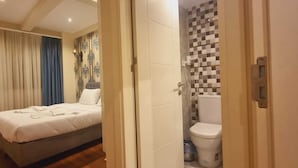 A bedroom with a bed, a bathroom with a toilet and shower, and a hallway with curtains. - By Historyal Hotel Due (Istanbul)