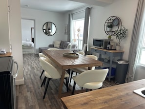 Une cuisine moderne avec une table en bois, des chaises blanches, un four à micro-ondes et une plante en pot.