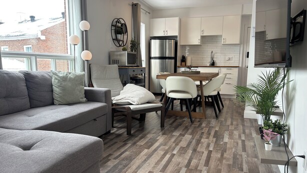 A modern kitchen with white cabinets, a dining area with a wooden table and chairs, a grey sofa, and a large window. - What a View!!! Chateau, Balcony incredible view of the Chateau! Free parking! (Lévis)