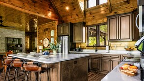 A spacious kitchen with a large island, wooden cabinets, and bar stools. - Heated Pool/HotTub/Games/Fire/Sleep 20+ (Sevierville)