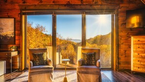 A cozy cabin room with two armchairs facing a large window overlooking a forested landscape. - Heated Pool/HotTub/Games/Fire/Sleep 20+ (Sevierville)