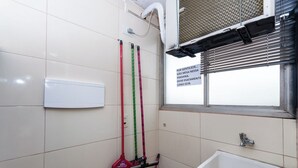 A bathroom with a white sink, a window with blinds, and three mop handles hanging on the wall. - Ad deactivated ad deactivated (Lapa de Baixo São Paulo)