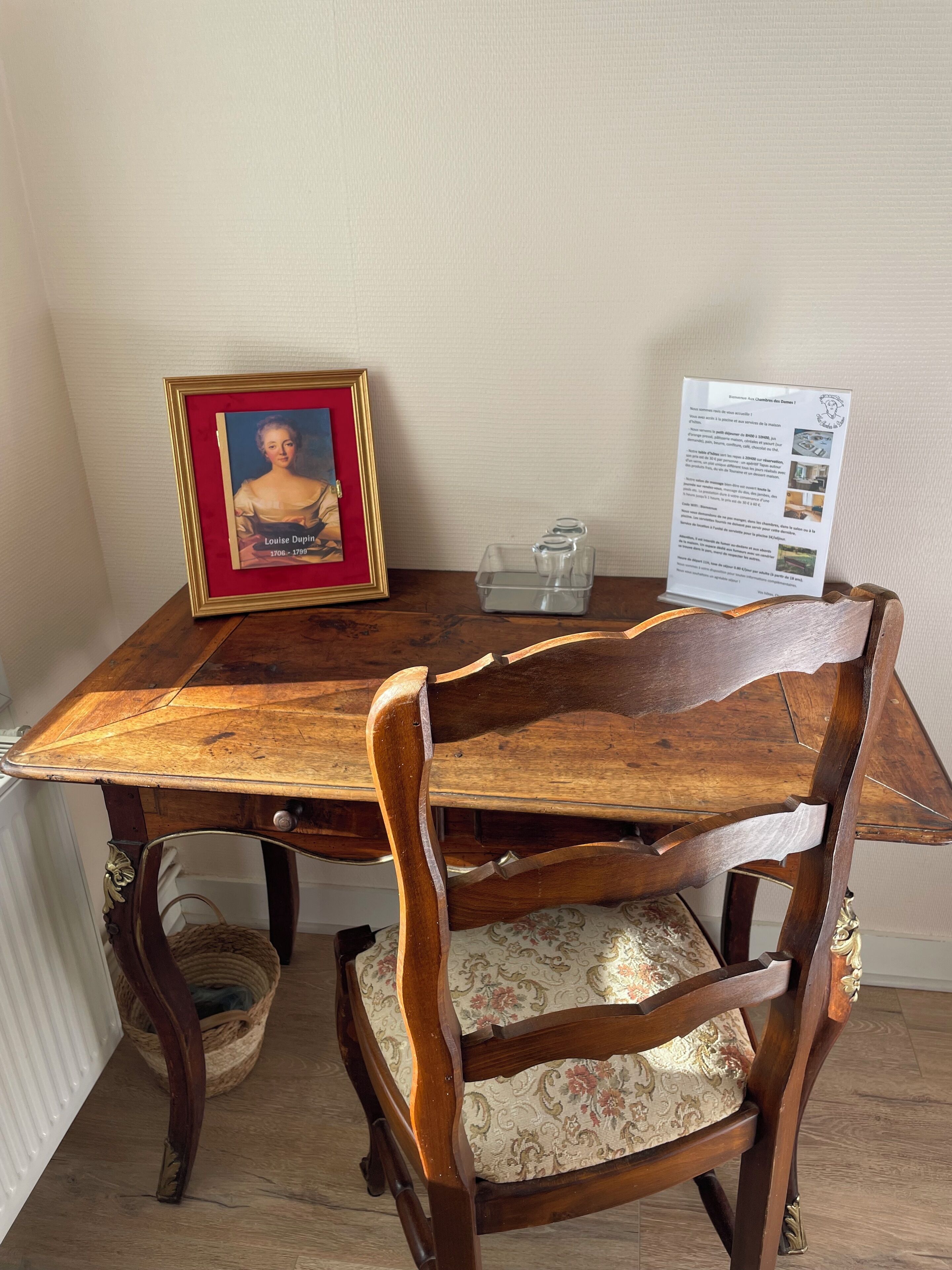A wooden dining table with a framed portrait and a menu.
