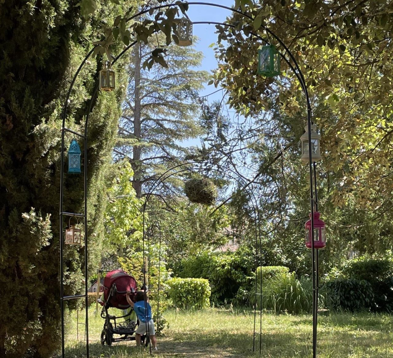 A covered pathway in a park with a stroller and a child.