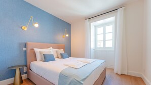 A bedroom with a bed, bedside table, and two wall-mounted lamps. - FLH Funchal A Quinta do Conde Flat II (Funchal)