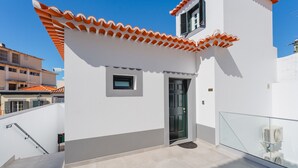 A modern building with a white facade, a tiled roof, a small window, and a door. - FLH Funchal A Quinta do Conde Flat II (Funchal)