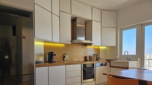 Een moderne keuken met roestvrijstalen apparatuur, houten aanrecht en uitzicht op de stad door een groot raam.