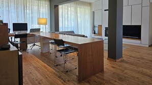 Een moderne keuken met een houten keukeneiland, een eethoek met een lange tafel en stoelen, en een ingebouwde open haard.