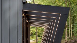 A modern architectural structure with a linear design and illuminated lines. - Fauna Bluff, A cliffside 2-bedroom modern cottage overlooking a bubbling stream. (Loudonville)