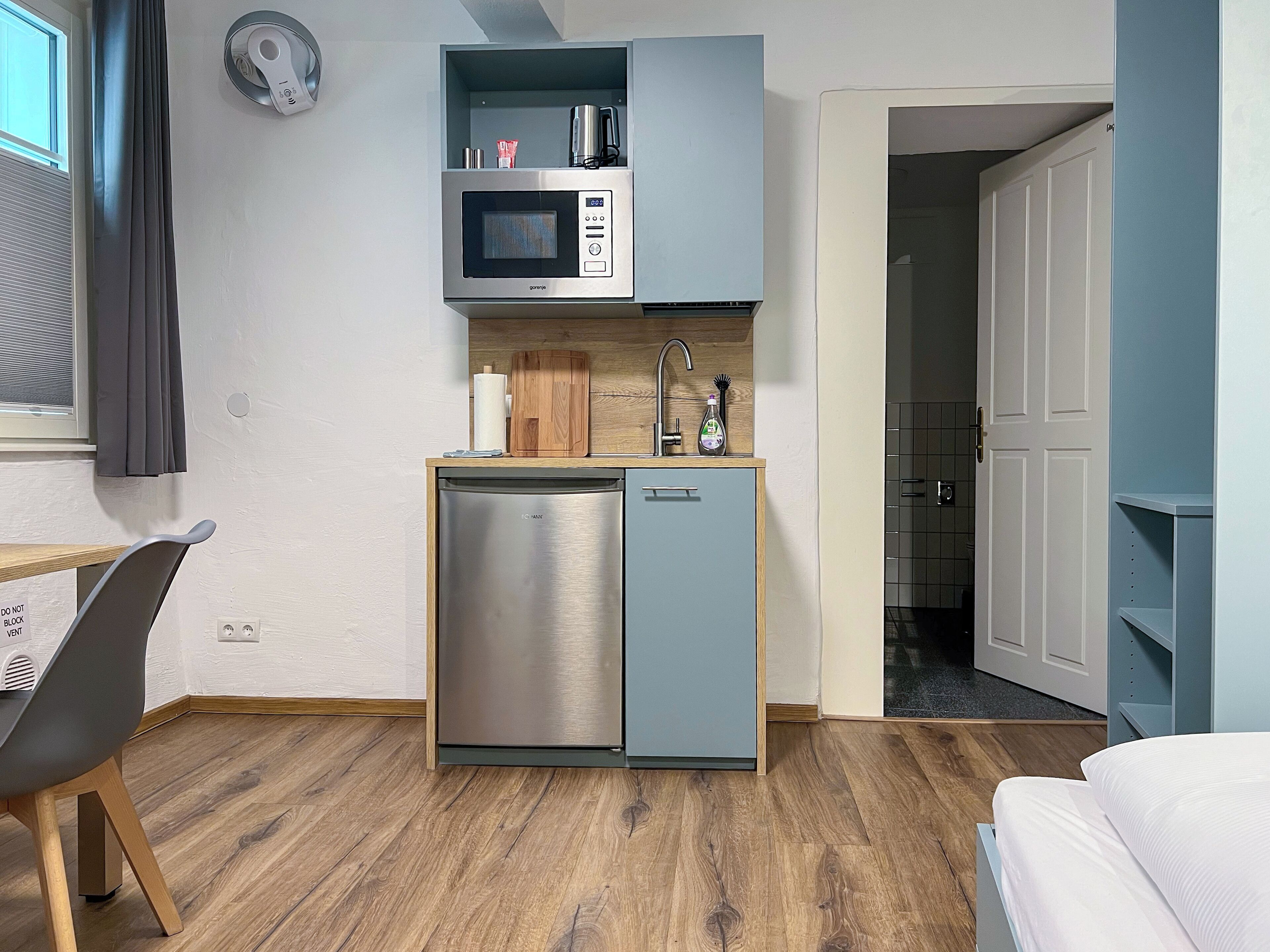 A compact kitchenette with a microwave, sink, and dishwasher.