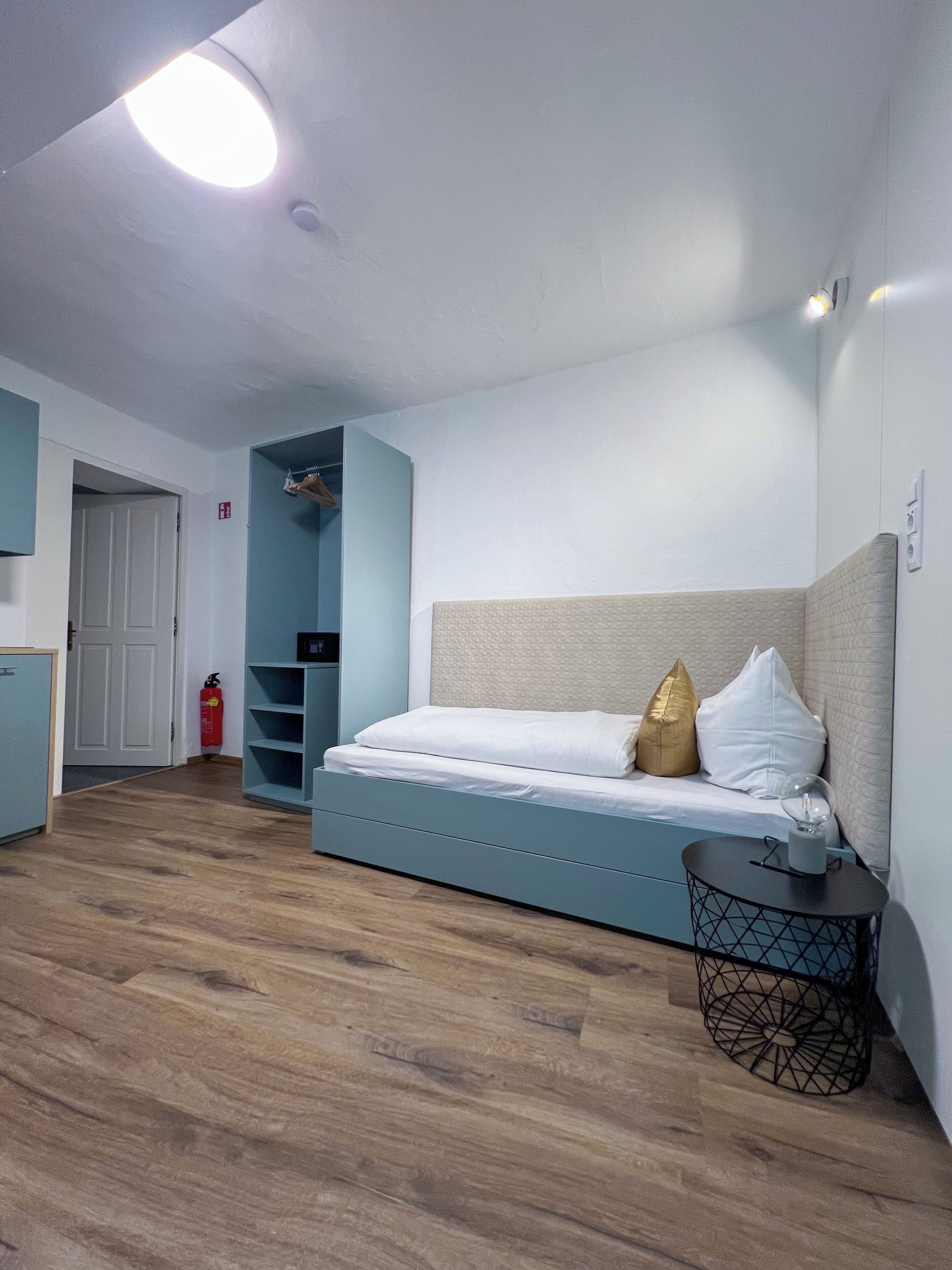 Un dormitorio moderno con cama, mesita de noche, armario y puerta.