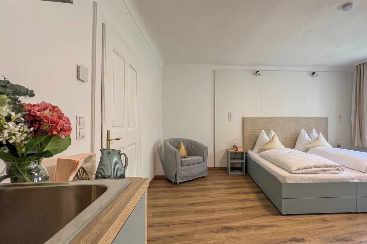 Une chambre moderne avec un grand lit, une table de chevet, une chaise et une fenêtre.