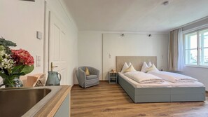 A modern bedroom with a large bed, a bedside table, a chair, and a window.