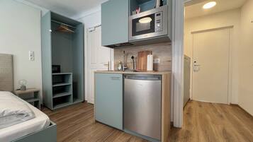 A compact kitchenette with a microwave, sink, and storage cabinets.