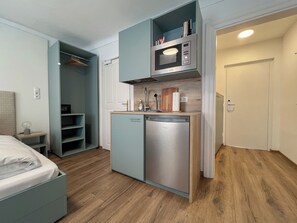 A compact kitchenette with a microwave, sink, and storage cabinets.