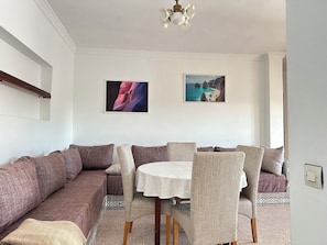 Relax in this stylish living room with a comfortable sofa, dining table, and ceiling fan.